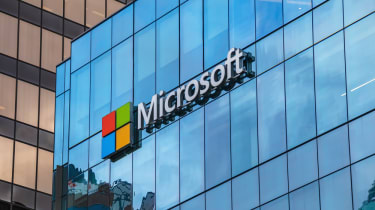 The Microsoft logo as seen in large print fixed onto a glass building
