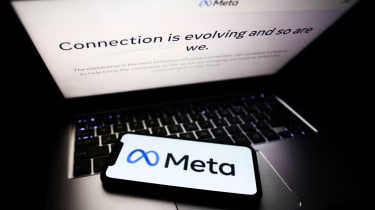 A smartphone lying on a laptop displaying the Meta company logo