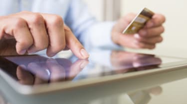 Man holding credit card making online payment on a tablet