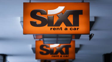 Sixt rental car company signs affixed to a ceiling