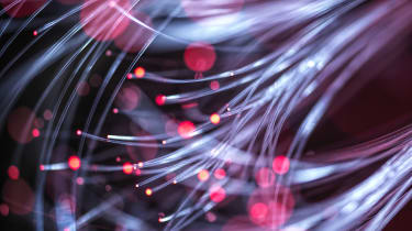 A close-up shot of a bundle of fibre optic cables, with red light shining through each cable