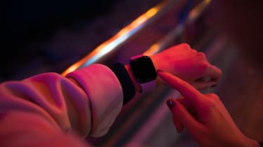 A smartwatch on someone&#039;s arm, lit in red