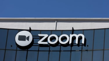 A telephoto shot of the Zoom logo on a glass building, with blue sky above