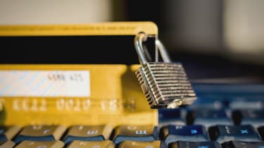 A padlock clipped on a yellow credit card perched on a keyboard 